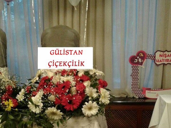 Beyaz örtülü nikâh masasının önünde, Gülistan Çiçekçilik kartı taşıyan geniş çiçek aranjmanı